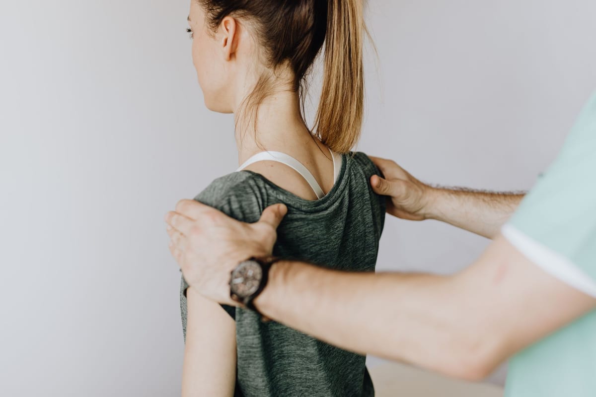 A therapist setting a standing patient's shoulder blades